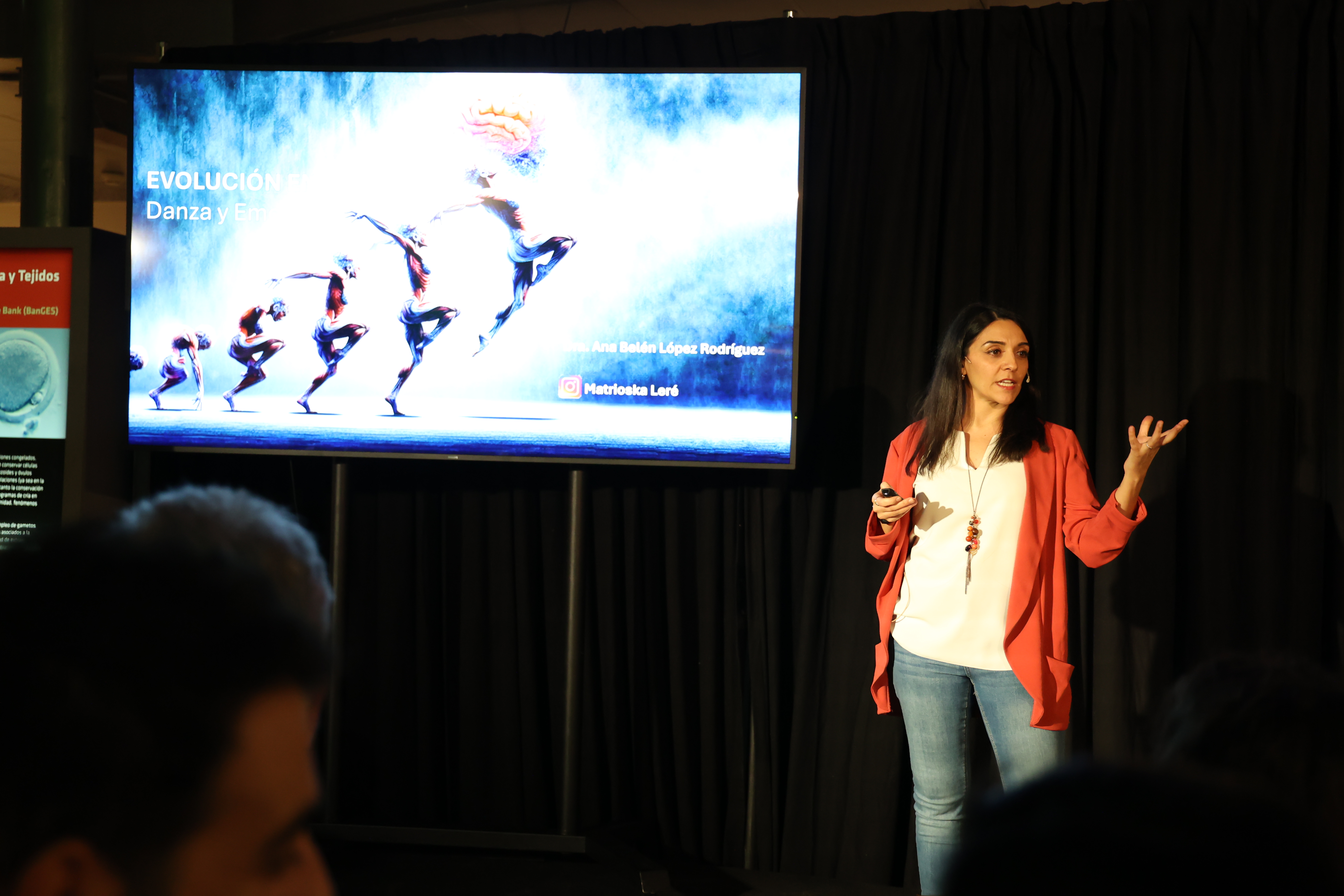Imagen de una mujer realizando la actividad, hablando junto a un monitor con imágenes de la musculatura humana en movimiento