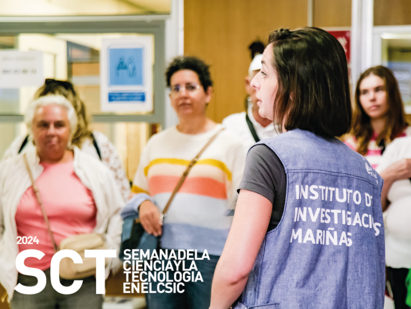 Una trabajadora del instituto de investigacións Mariñas, comeza unha visita guiada ao centro coas persoas visitantes de fondo.